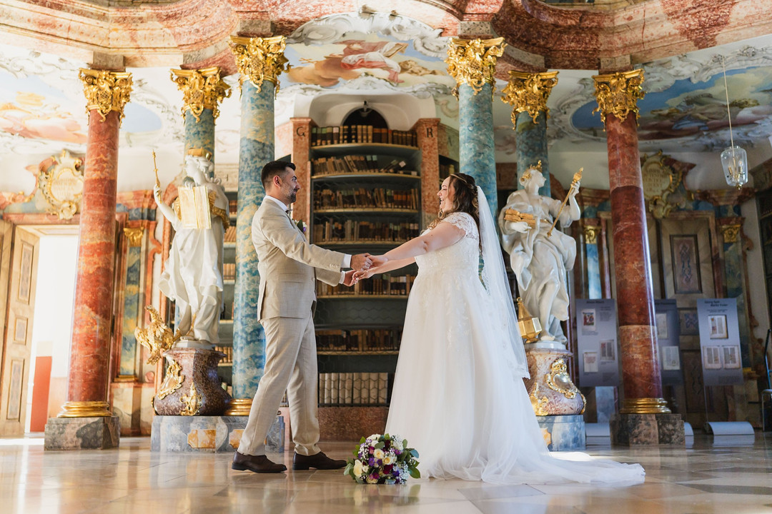 Hochzeit Kloster Wiblingen: First Look im Bibliothekssaal, Braut und Bräutigam reichen sich die Hände