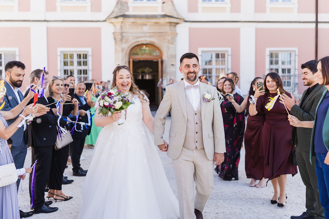 Hochzeit Kloster Wiblingen: Brautpaar läuft lachend durch das Spalier der Gäste vor dem Kloster