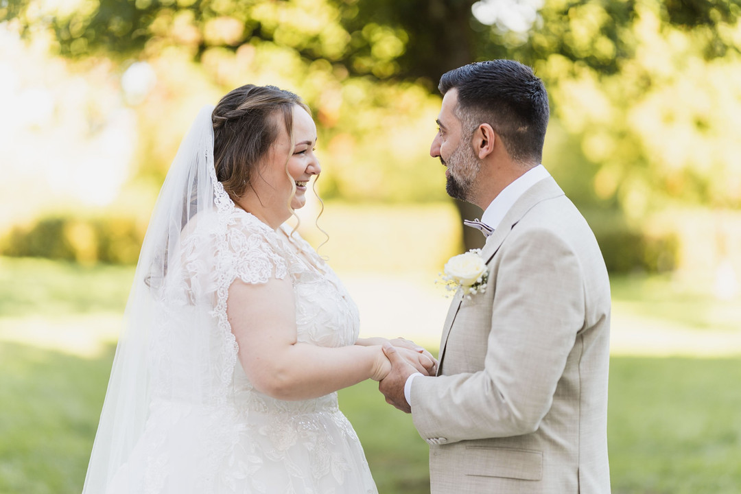 Hochzeit Kloster Wiblingen: Brautpaarshooting im Garten: Braut und Bräutigam halten sich lachend an den Händen